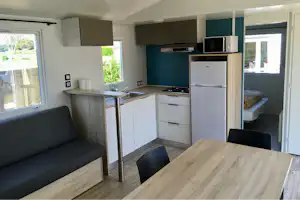 Camping de La Côte des Légendes - Innenraum eines Mobilheims mit Kochnische und Sitzgelegenheiten