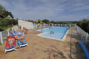 Großer Camping-Pool mit Liegen, blauen Umrandungen und mehreren Kindern im Wasser auf einer Terrasse.