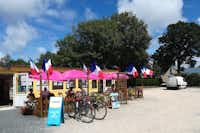 Camping De Lanven - Minimarkt und Bistro des Campingplatzen mit Sitzgelegenheiten und Sonnenschirmen davor