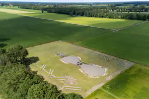 Luftaufnahme eines Campingplatzes mit zwei kleinen Teichen, Wiesen, Wegen und umgebenden Feldern und Bäumen.