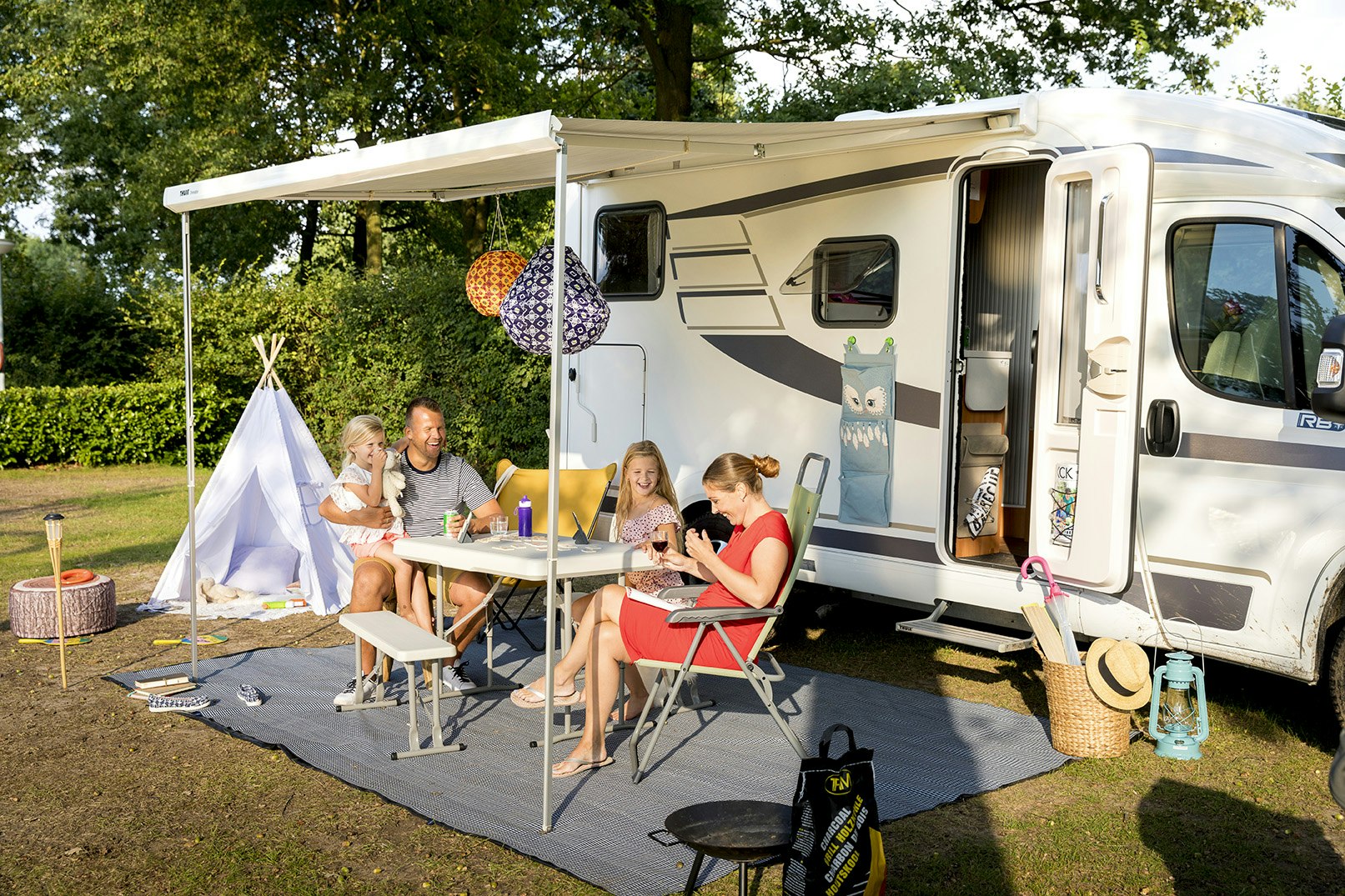 Camping De Leistert - Familie sitzt auf ihrem Standplatz am Tisch