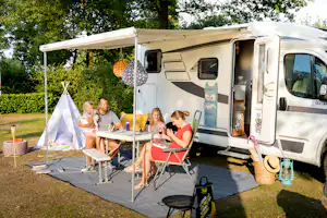 Camping De Leistert - Familie sitzt auf ihrem Standplatz am Tisch