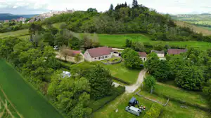 Campinganlage im Grünen mit mehreren Gebäuden, Wegen und Stellplätzen, umgeben von Wiesen und Bäumen im Tal.