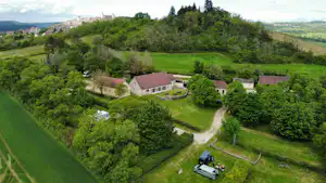 Campinganlage im grünen Tal mit mehreren Gebäuden, Wegen und Rasenflächen, umgeben von Bäumen und Hügeln.