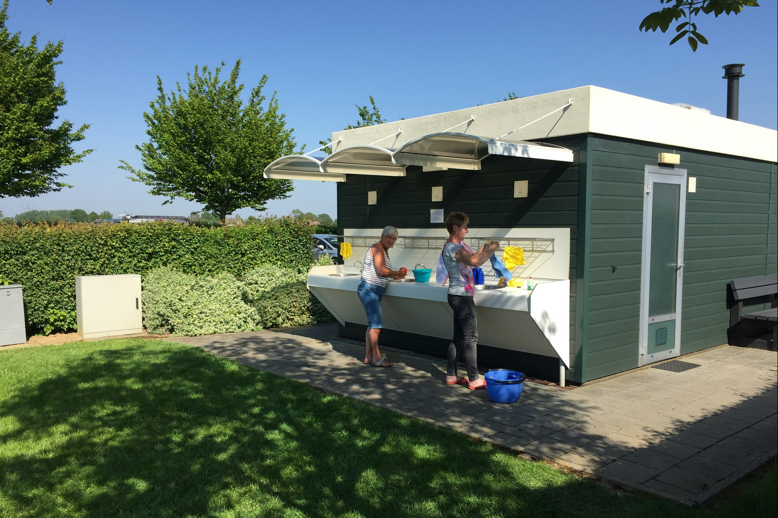 Camping De Maashoeve  - Camper am Waschbecken vom Sanitärgebäude