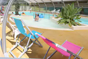 Camping De Matignon - überdachter Poolbereich mit Begrünung und Liegestühlen