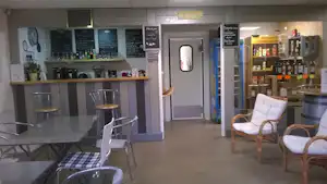 Barbereich in einer Camping-Lounge mit Tresen, Stühlen, Regalen mit Getränken und Sitzgelegenheiten im Innenraum.