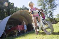 Camping de Norgerberg  - Kind mit Fahrrad am Mobilheim vom Campingplatz auf grüner Wiese