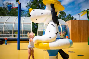 Camping De Papillon - Kind begrüßt eine Statue des Campingplatzmaskottchens im Außenbereich des überdachten Pools