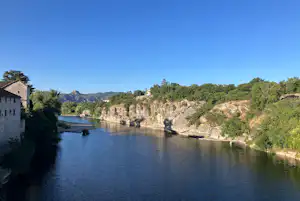 Breiter Fluss im Tal mit bewaldeten Hängen, Felswänden und einem kleinen Boot im Wasser.