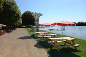Camping de Thoissey - gejieste Promenande mit von Sonnenschirmen geschützten Picknick-Tischen am Ufer des Flusses