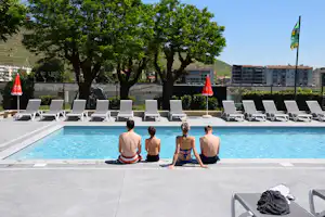Camping de Tournon HPA - Camper am Pool vom Campingplatz mit Sonnenschirmen und Liegestühlen