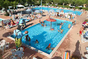 Großes Camping-Schwimmbad mit blauem Wasser, Springbrunnen, vielen Liegen und Sonnenschirmen, im Hintergrund weitere Pools.