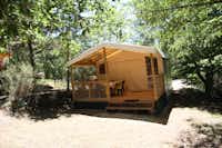 Camping Des Bastides - Mobilheim mit Veranda zwischen Bäumen auf dem Campingplatz