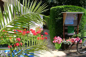 Camping Des Chaumières - Rezeption vom Campingplatz mit Infotafel, Blumen und Fahrrad