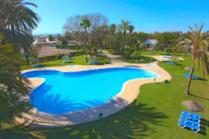 Camping Devesa Gardens Resort Wasserrutsche - Pool vom Campingplatz mit Sonnenschirmen und Liegestühlen auf grüner Wiese