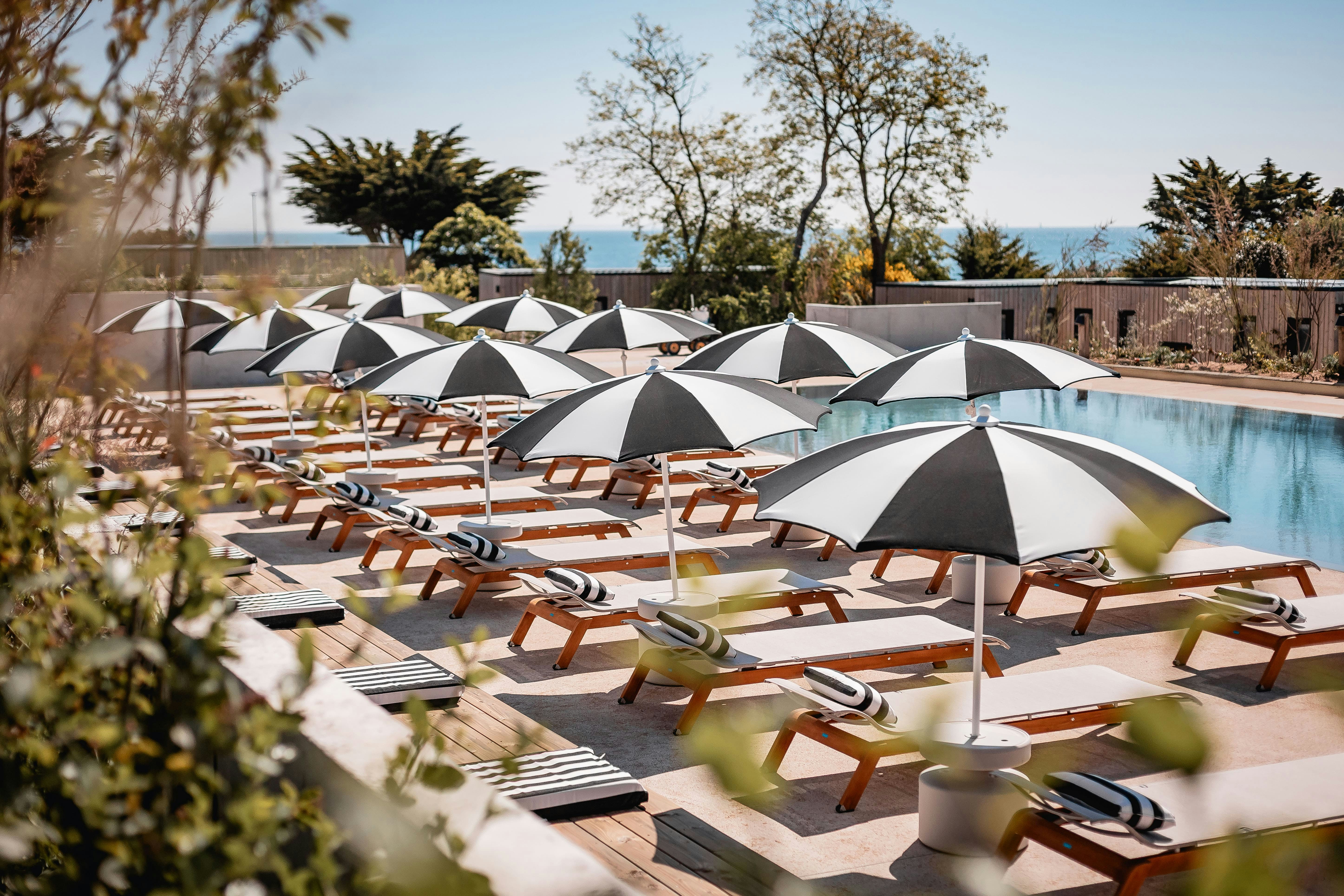 Sauvage  - Pool im Freien mit Liegestühlen und Sonnenschirmen