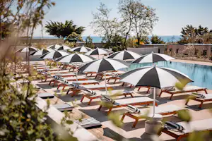 Sauvage - Pool im Freien mit Liegestühlen und Sonnenschirmen