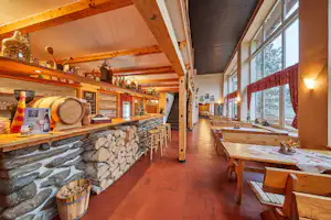 Camping Dolce - Innenansicht des Restaurants mit Holztischen und großen Fenstern