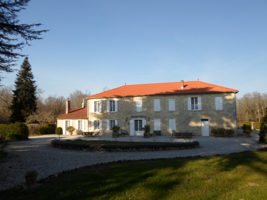 Campinghaus mit rotem Ziegeldach, weißen Fensterläden und gepflegtem Rasen, davor ein gepflasterter Weg und niedrige Stufen.