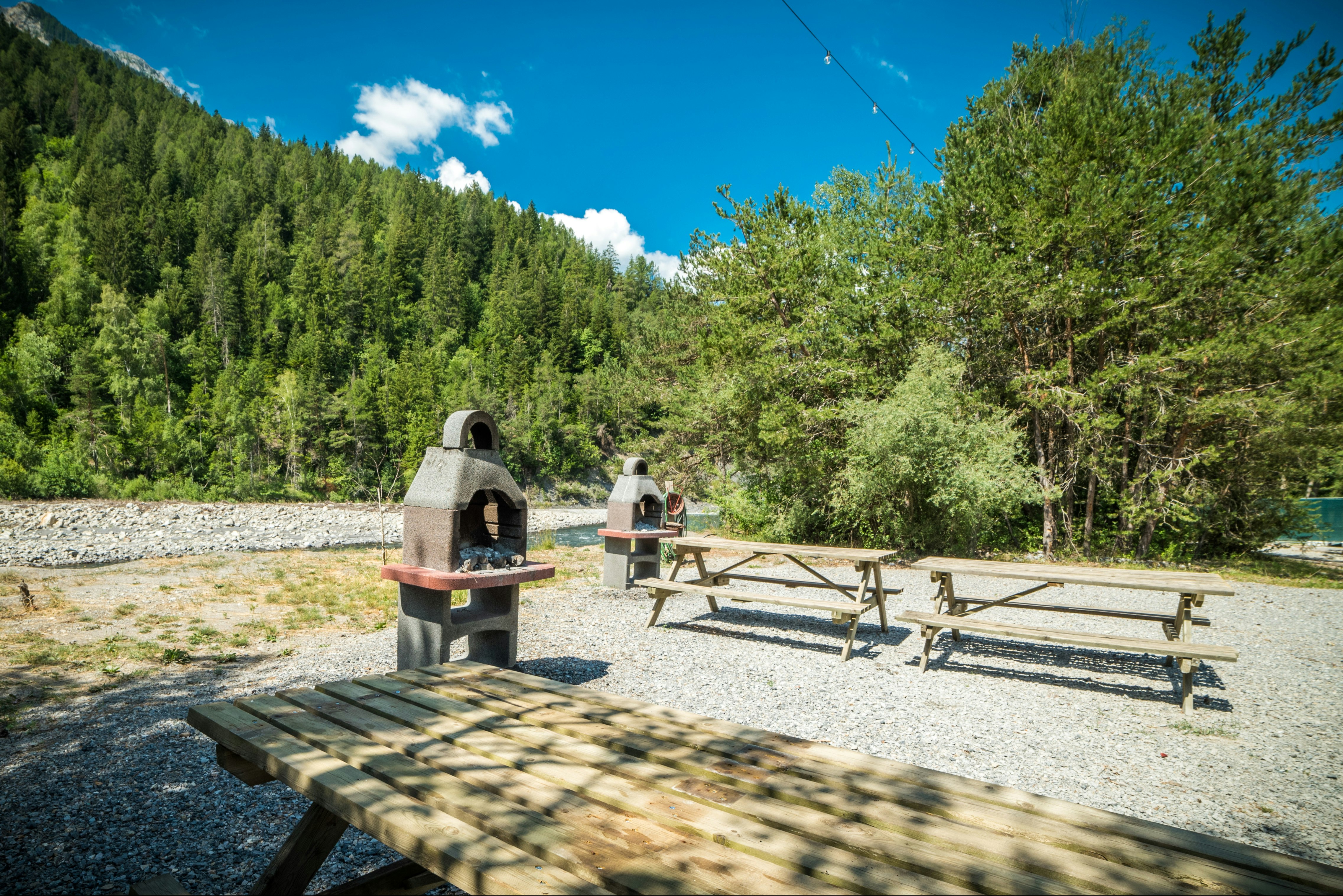 Camping Domaine Loisirs de l'Ubaye  Camping Domaine Loisirs de l' Ubaye - Grillstelle mit Picknickbänken auf dem Campingplatz