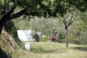 Camping Domaine Sainte Madeleine - Zelt auf Stellplatz im Grünen mit davor sitzenden Campern