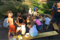 Camping Drei Spatzen - Kinder rösten Marshmallows an einem Lagerfeuer auf dem Campingplatz