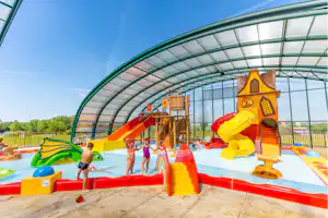 Bunter Spielbereich für Kinder unter einem transparenten Zeltdach: Hüpfburg, Rutsche und Spielgeräte auf dem Campingplatz.