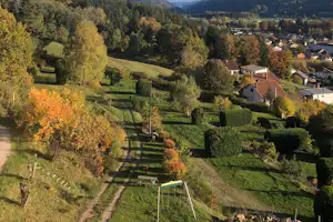 Blick ins Tal mit grünen Wiesen, einzelnen Häusern und Bergen in der Ferne, aufgenommen vom Campingplatz.