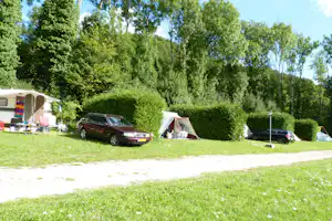 Camping du Gît - Stellplätze umringt von Hecken an einer Strasse des Campingplatzes