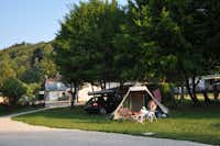 Camping du Gît - Zelt unter Bäumen auf einem Stellplatz