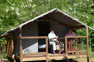 Camping du Lac - Camper auf der Veranda vom Campingplatzom Mobilheim auf dem Campingplatz im Grünen