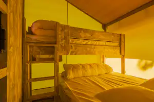 Etagenbett in einem Campingzelt mit Matratzen, Kissen und Holzrahmen, Blick auf die Schlafplätze.