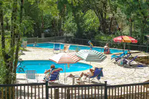 Camping du Ruisseau du Treil - Camper am Pool vom Campingplatz mit Sonnenschirmen und Liegestühlen