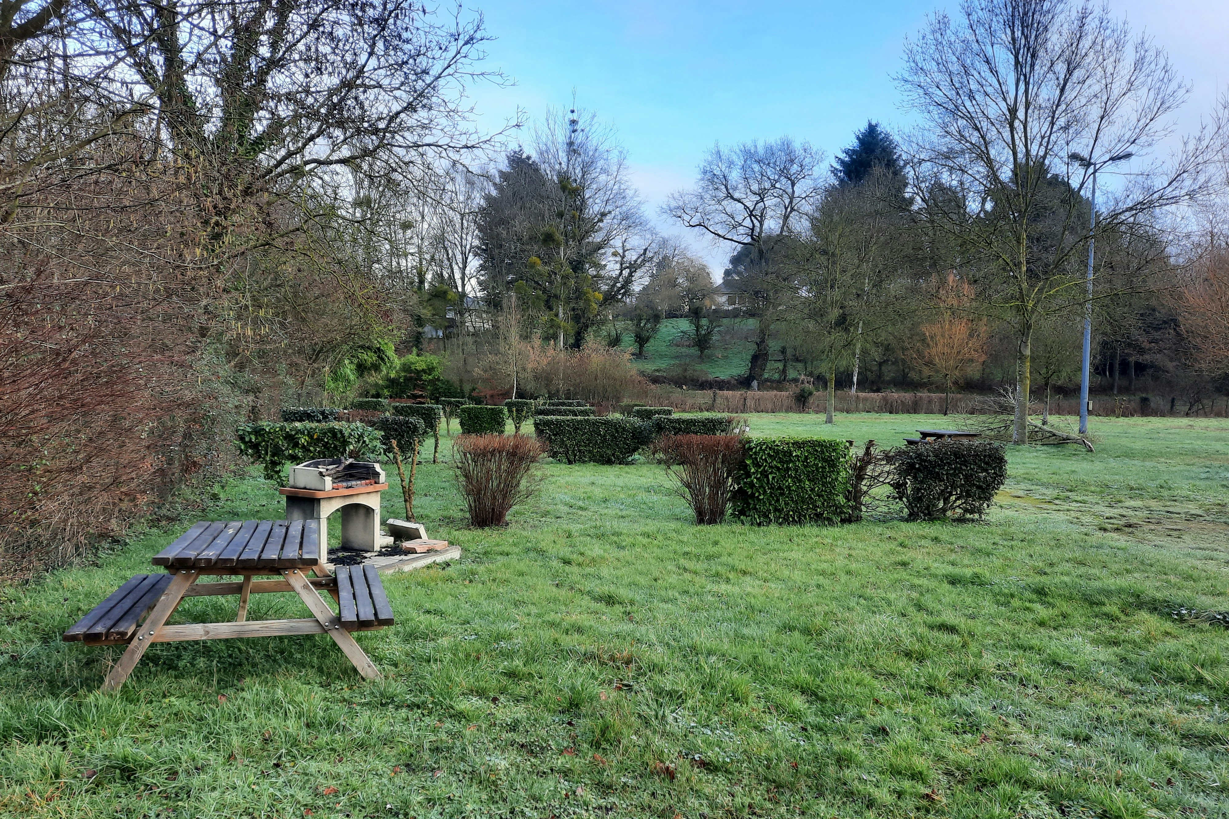 Camping du Val Joyeux - Standplätze durch leichten Heckenbewuchs voneinander abgetrennt und eine Picnic-Bank mit Grillstelle