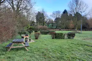 Camping du Val Joyeux - Standplätze durch leichten Heckenbewuchs voneinander abgetrennt und eine Picnic-Bank mit Grillstelle