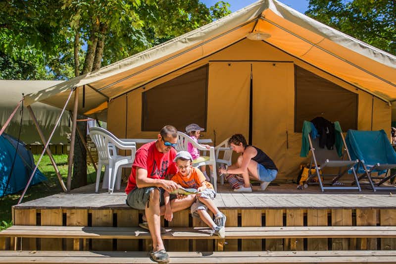 Camping du Ventoulou - Glamping Safarizelt mit Veranda auf der eine Familie sitzt