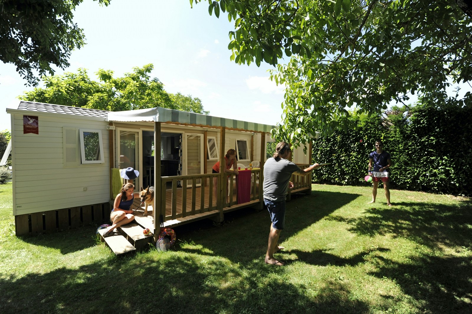 Camping du Ventoulou - Mobilheim mit überdachter Veranda, vor der zwei Camper spielen