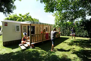 Camping du Ventoulou - Mobilheim mit überdachter Veranda, vor der zwei Camper spielen