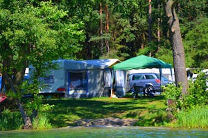 Camping Dłużek (Nr. 135) - Campingbereich für Zelte, Wohnwagen und Mobilheime im Schatten der Bäume und blick auf den See