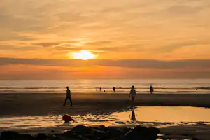 Camping Duinezwin - Gäste spazieren bei Sonnenuntergang am Strand