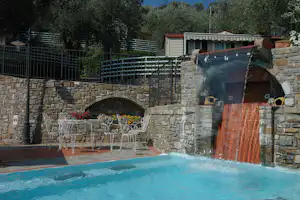 Camping Edy - Pool mit Wasserfall und Sitzgruppe in der Sonne