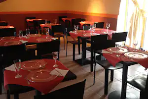Restaurantbereich im Camping: gedeckte Tische mit roter Tischdecke, schwarzem Stuhl und Geschirr, an der Wand hängen Deko-Schilder.