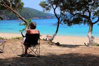 Camping Enjoy Lichnos - Camper sitzen im Schatten mit Blick auf das Meer