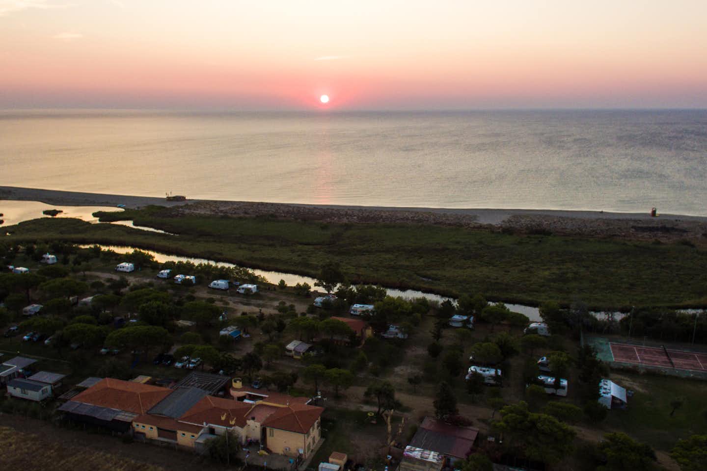 Camping Ermosa  -  Luftaufnahme vom Campingplatz am Fluss und am Mittelmeer auf Sardinien bei Sonnenuntergang