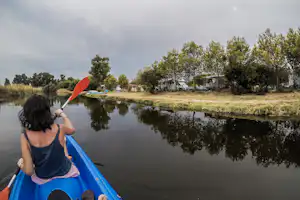 Camping Ermosa - Camper beim Kanufahren auf dem Fluss entlang vom Wohnwagen- und Zeltstellplatz des Campingplatzes