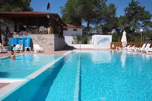 Camping Europa - Poolbereich mit Liegestühlen und Sonnenschirmen am Rand