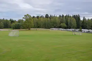 Rasenfläche mit zwei Fußballtoren, im Hintergrund Stellplätze mit Wohnwagen und Bäumen am Campingplatz.