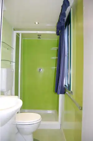 Camping-Badezimmer mit Dusche, Duschwand, WC und Waschbecken im hellen Raum.