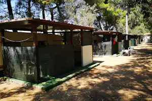 Carport am Campingplatz mit Sichtschutzwand, Stellplatz für Wohnmobil und Tisch im Schatten von Bäumen.